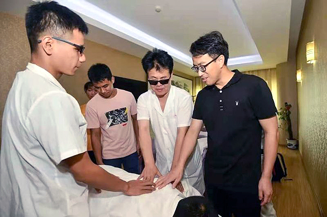 王永澄（右二）正在指导盲人学员按摩技法