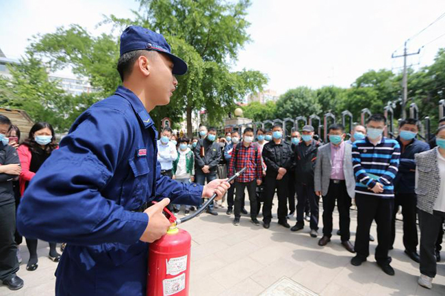 图为消防员讲解灭火器使用方法