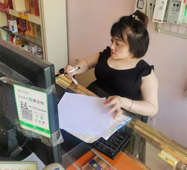 图为廖丹在店铺里查看账目
