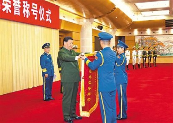 图为习近平向获得荣誉称号的单位颁授荣誉奖旗