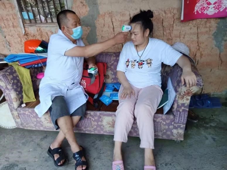 图为冯世财上门为隔离人员测体温
