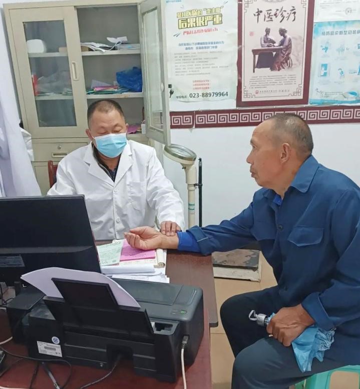 图为冯世财为患者把脉