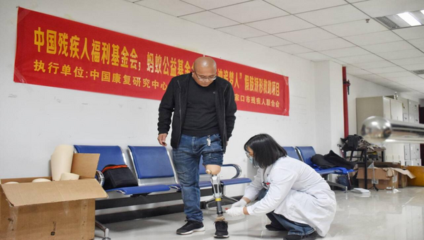 图为工作人员在活动中为残疾人适配假肢