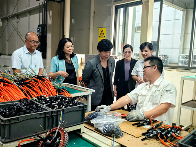 图为在绿源电动车生产车间走访残疾人工作者