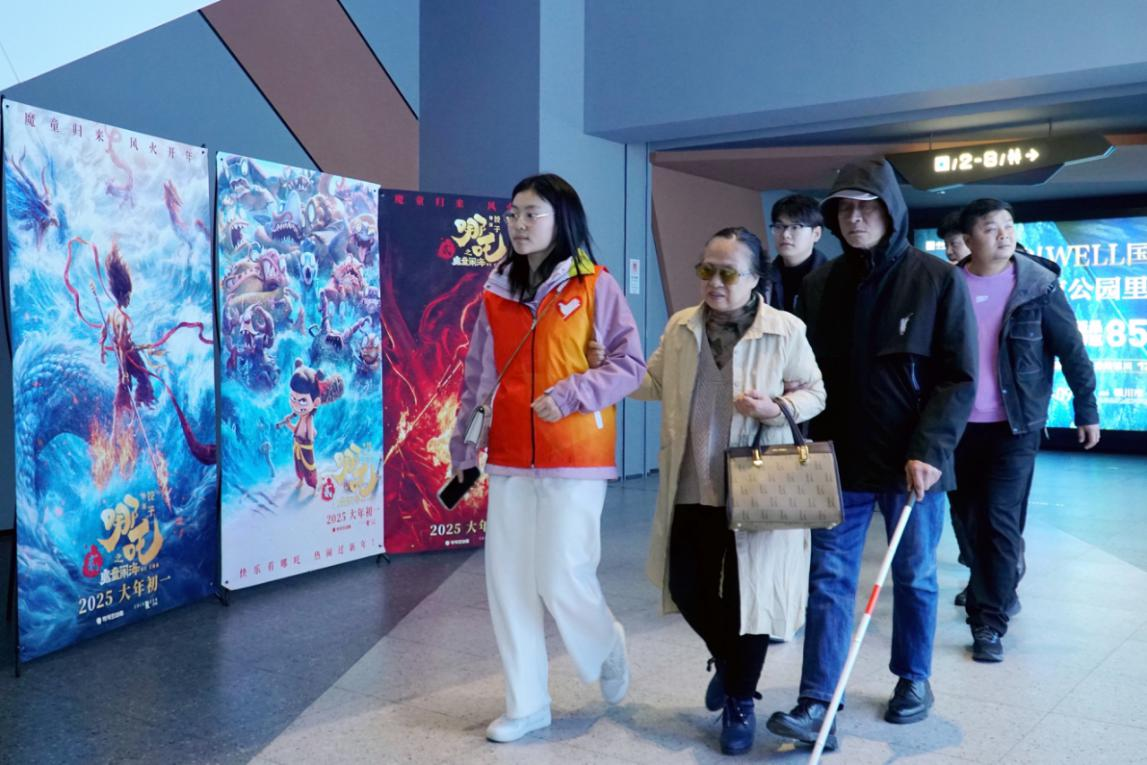 图为志愿者引导盲人进入影院