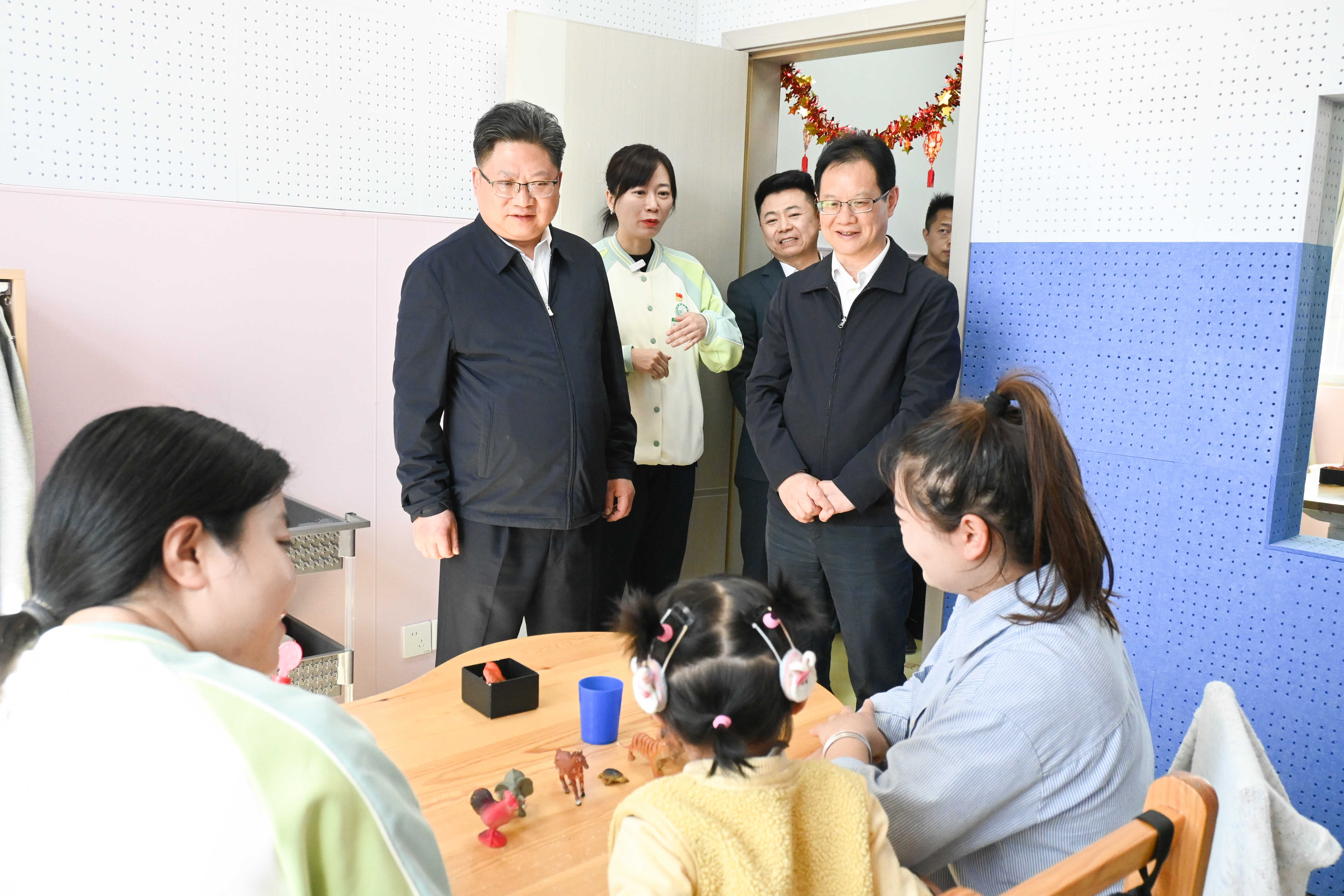 图为周代军了解儿童康复训练情况