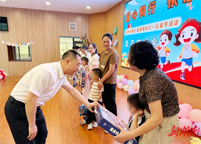 图为省残联党组书记、理事长黄进良在省残疾人康复研究中心与残疾儿童们互动