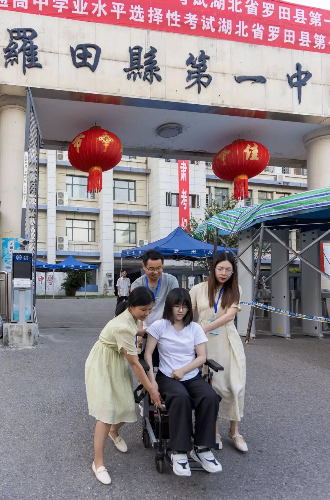 图为曹慧婷在妈妈张胜兰（左）、班主任熊晟（后）和送考老师的帮助下，坐着轮椅“走”出考场