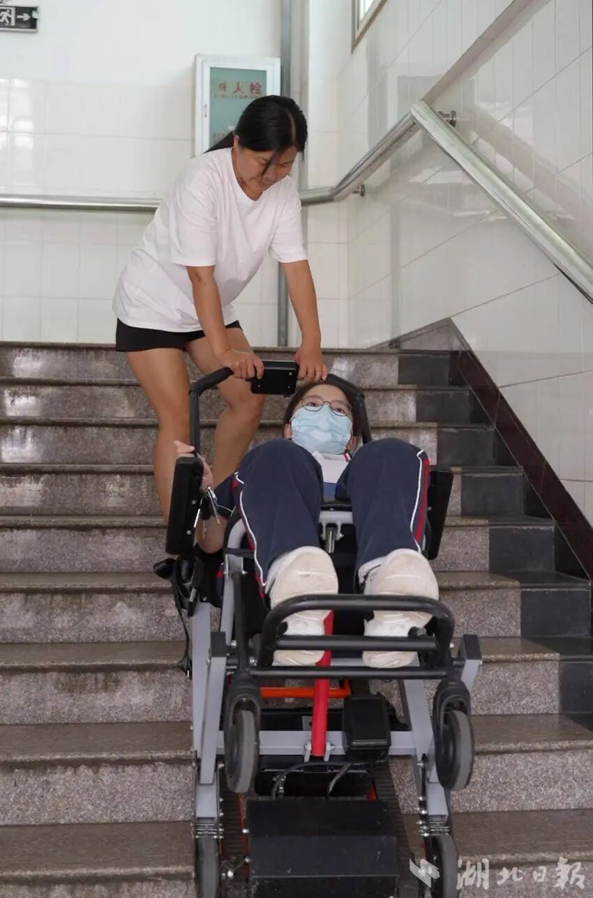 图为张胜兰用爬楼机拖着曹慧婷上下楼梯