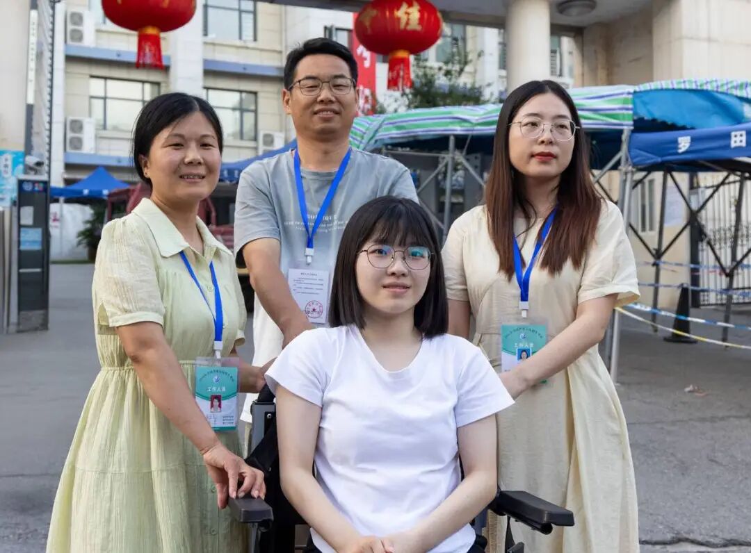 图为曹慧婷在妈妈张胜兰（左）、班主任熊晟（后）和送考老师的帮助下，坐着轮椅“走”出考场